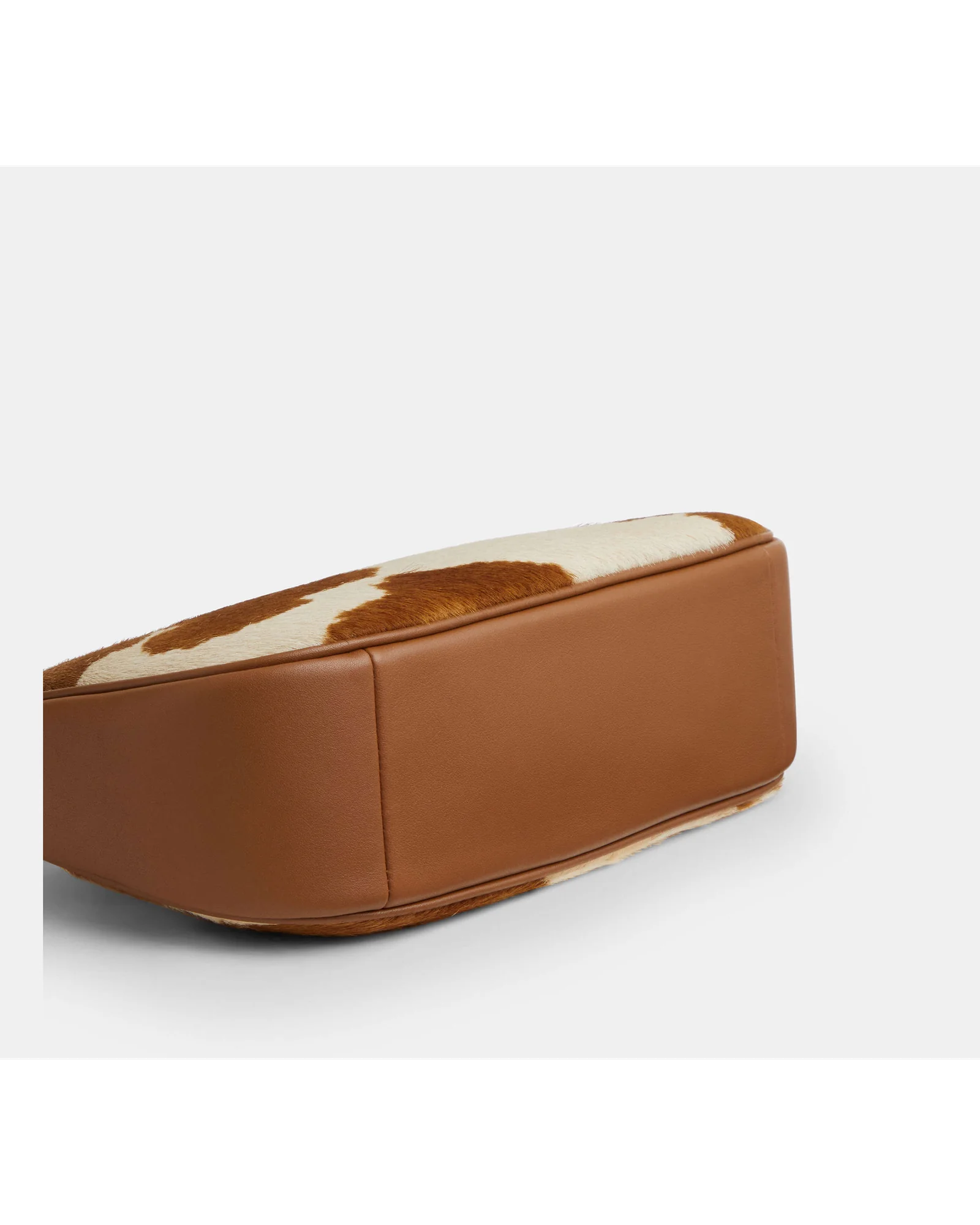 Днище сумки Coach Teri с коровьим принтом и кожаной отделкой.