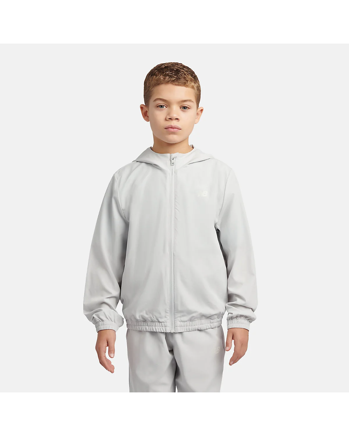 Куртка New Balance NB Essential Full Zip Track Jacket серая, фронтальный вид на модели.