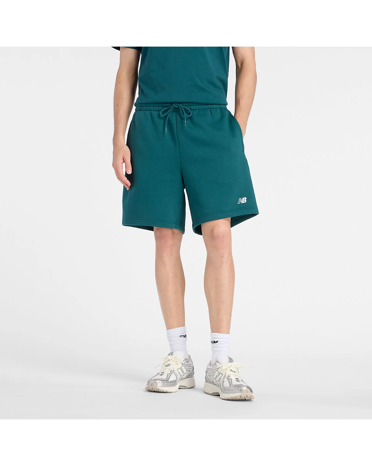 Зелёные мужские флисовые шорты New Balance с белой вышивкой, вид спереди.