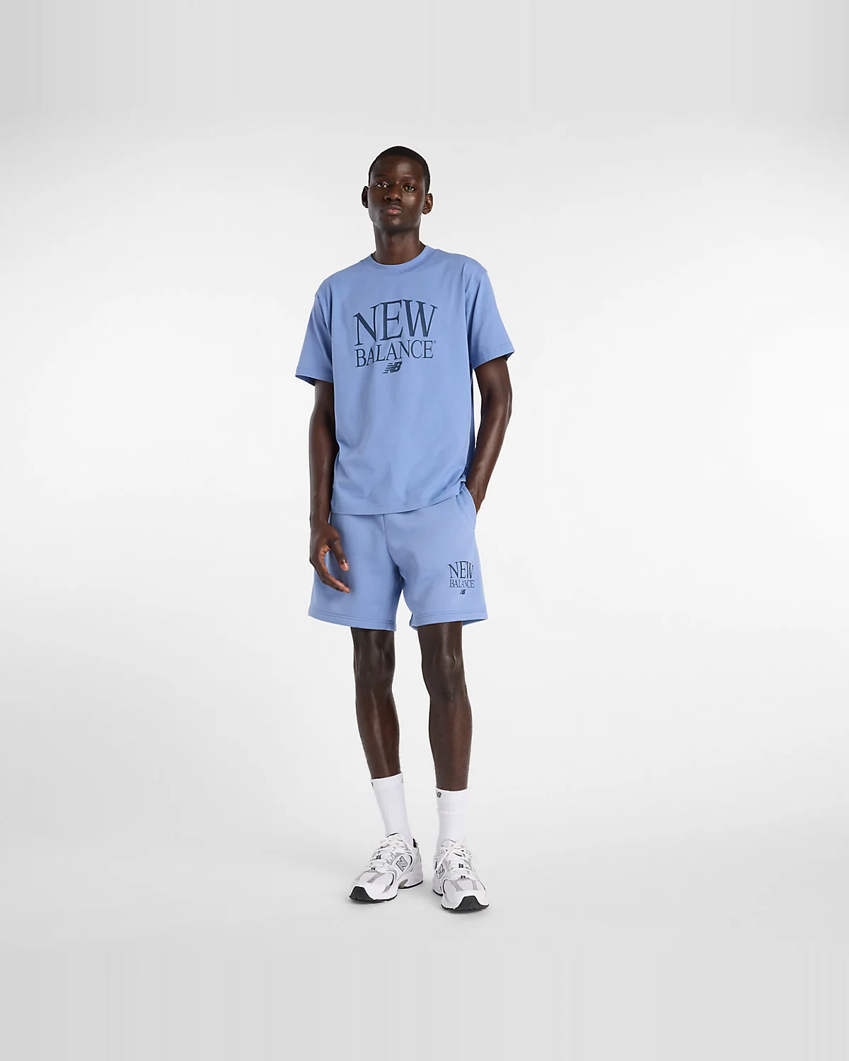 Крупный план белого фирменного принта New Balance на чёрной ткани футболки