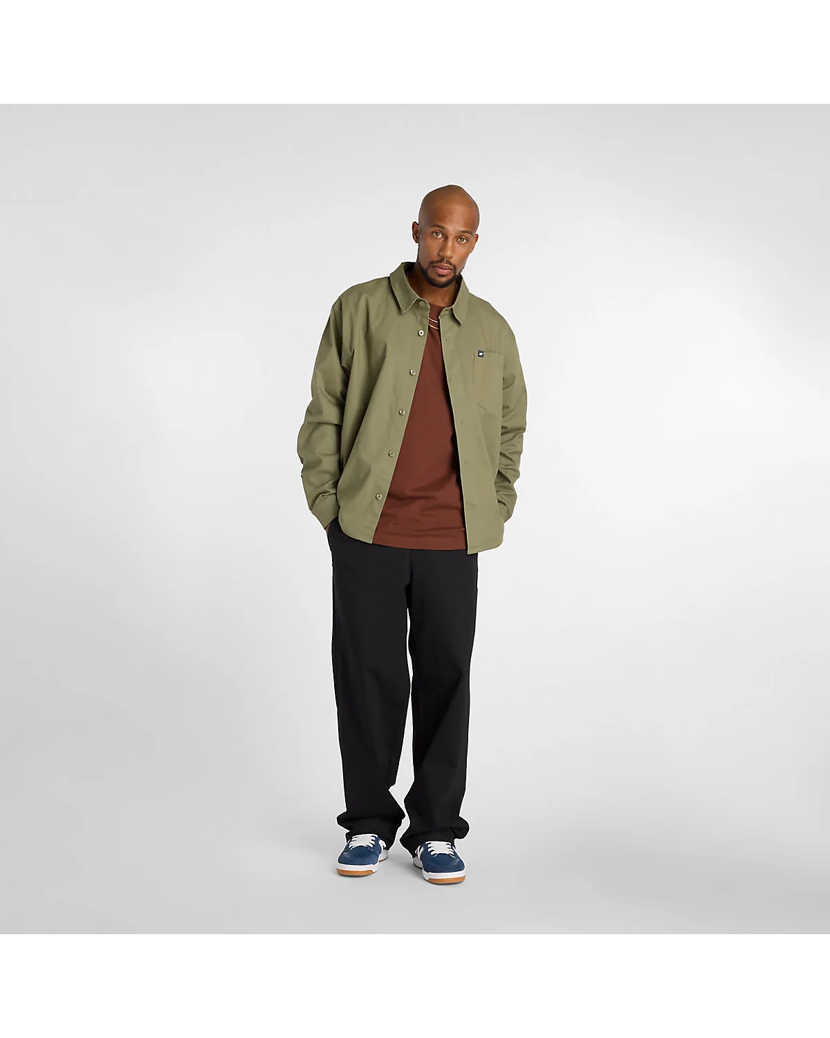 Коричневая футболка New Balance в полный рост с бейсболкой, боковой вид.