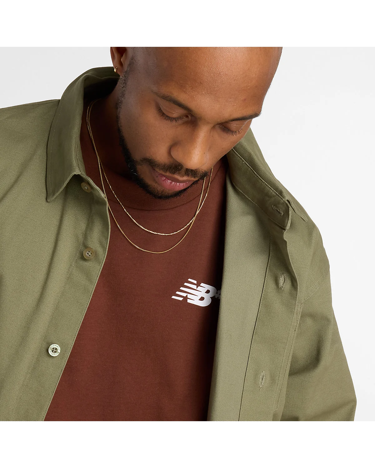 Вид сзади коричневой футболки New Balance с гладкой фактурой ткани.