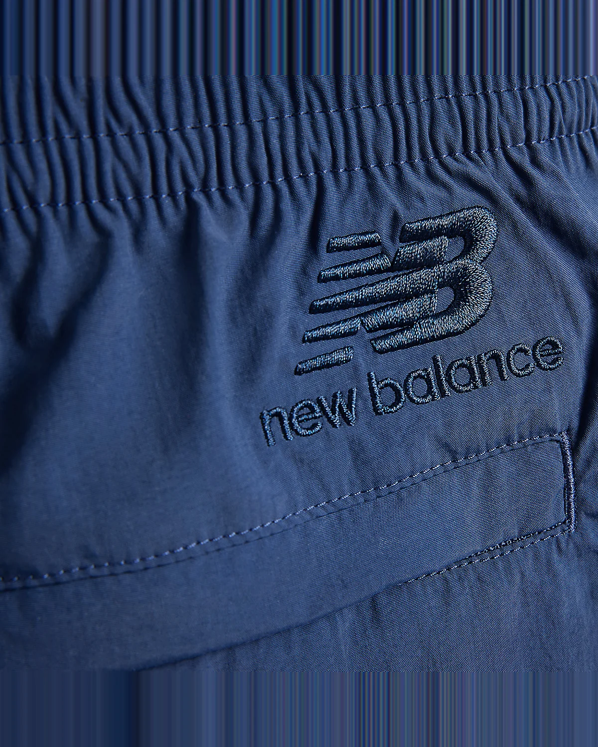 Крупный план талии серо-фиолетовых шорт New Balance со шнурком.