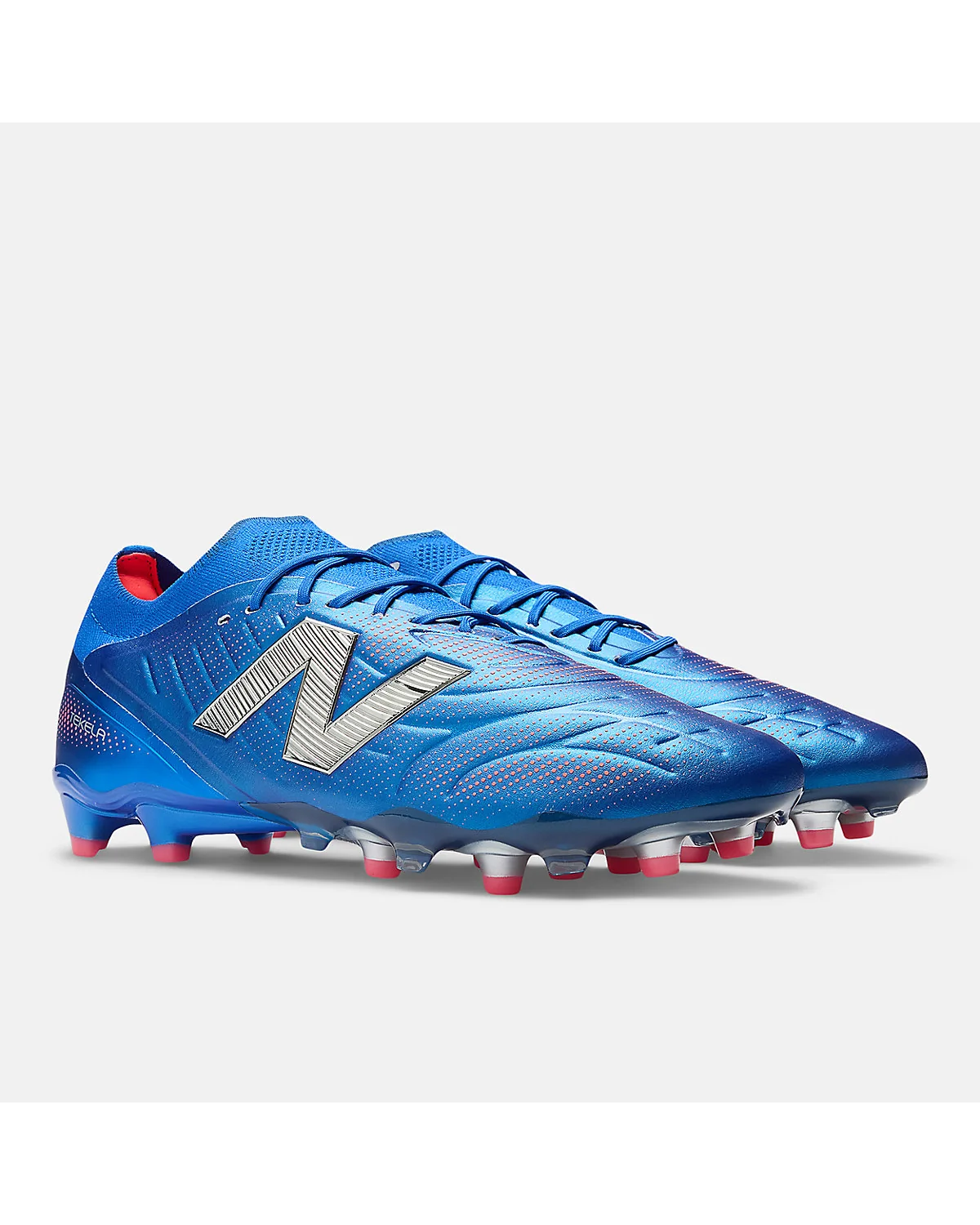 Синие бутсы New Balance Tekela Elite Low FG V5, другой угол обзора с видимыми шипами.
