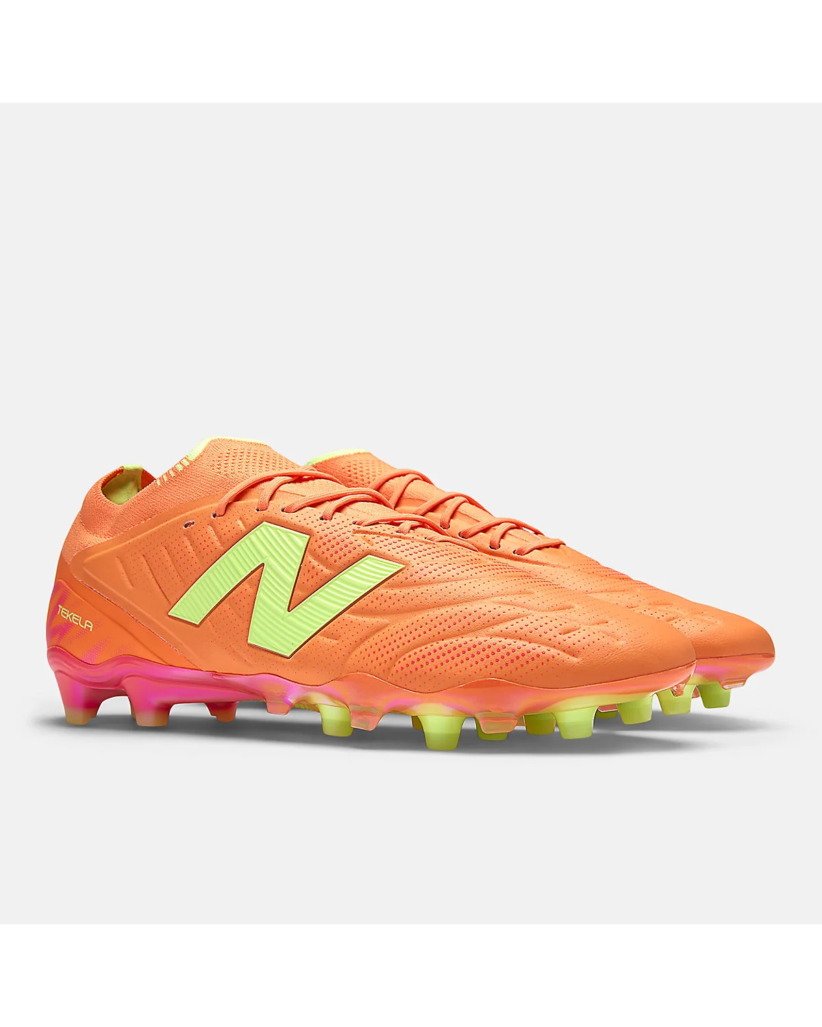 Футбольные бутсы New Balance в цвете манго с шипами, вид под углом.