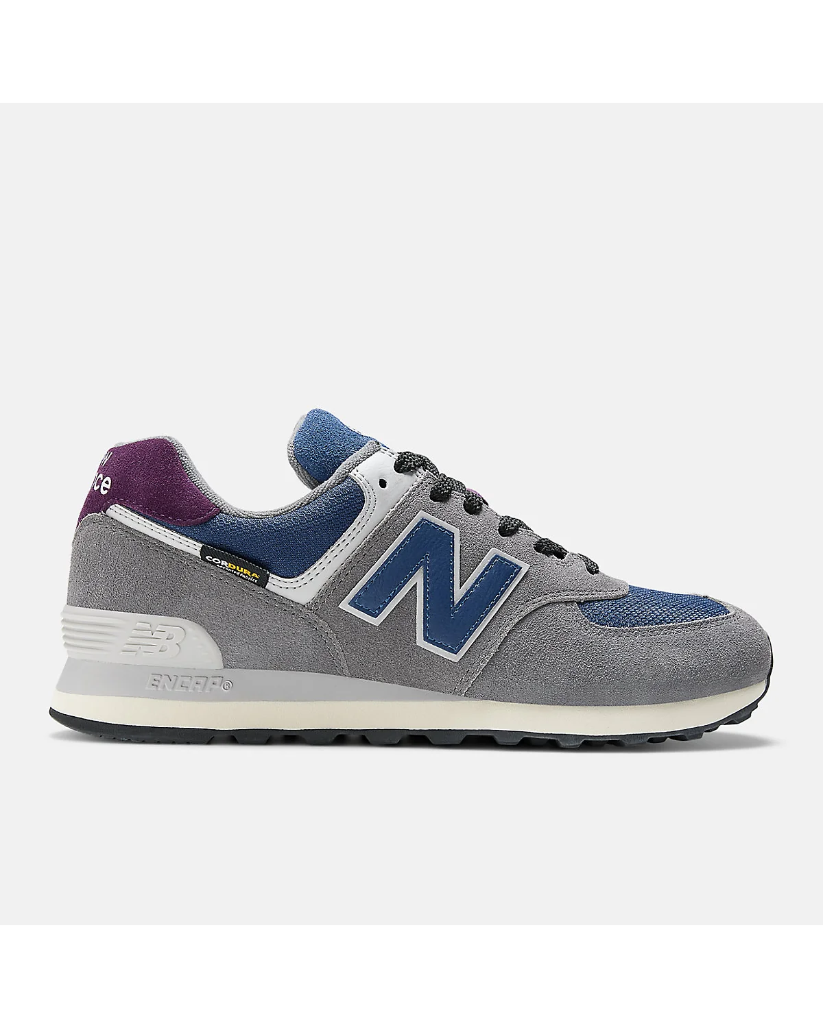Серые кроссовки New Balance 574 с синим контрастом на пятке, вид сбоку.