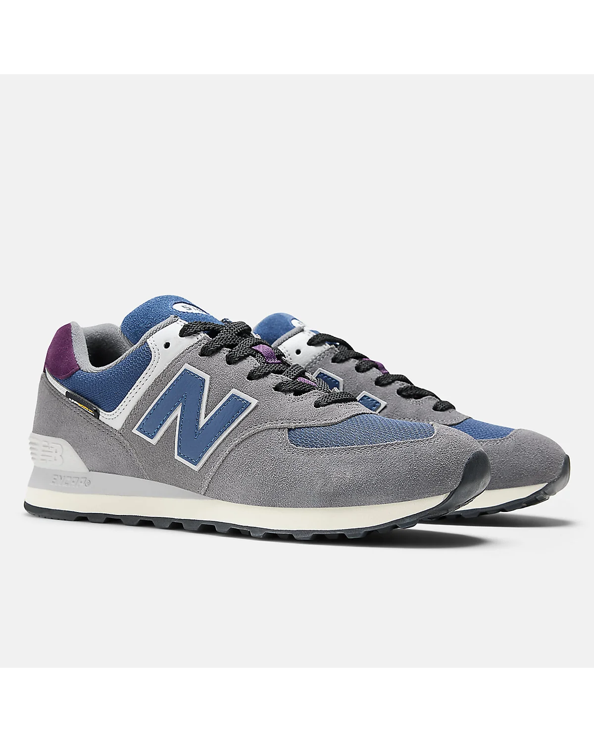 Серые кроссовки New Balance 574, трёхчетвёртный вид с синим контрастом.