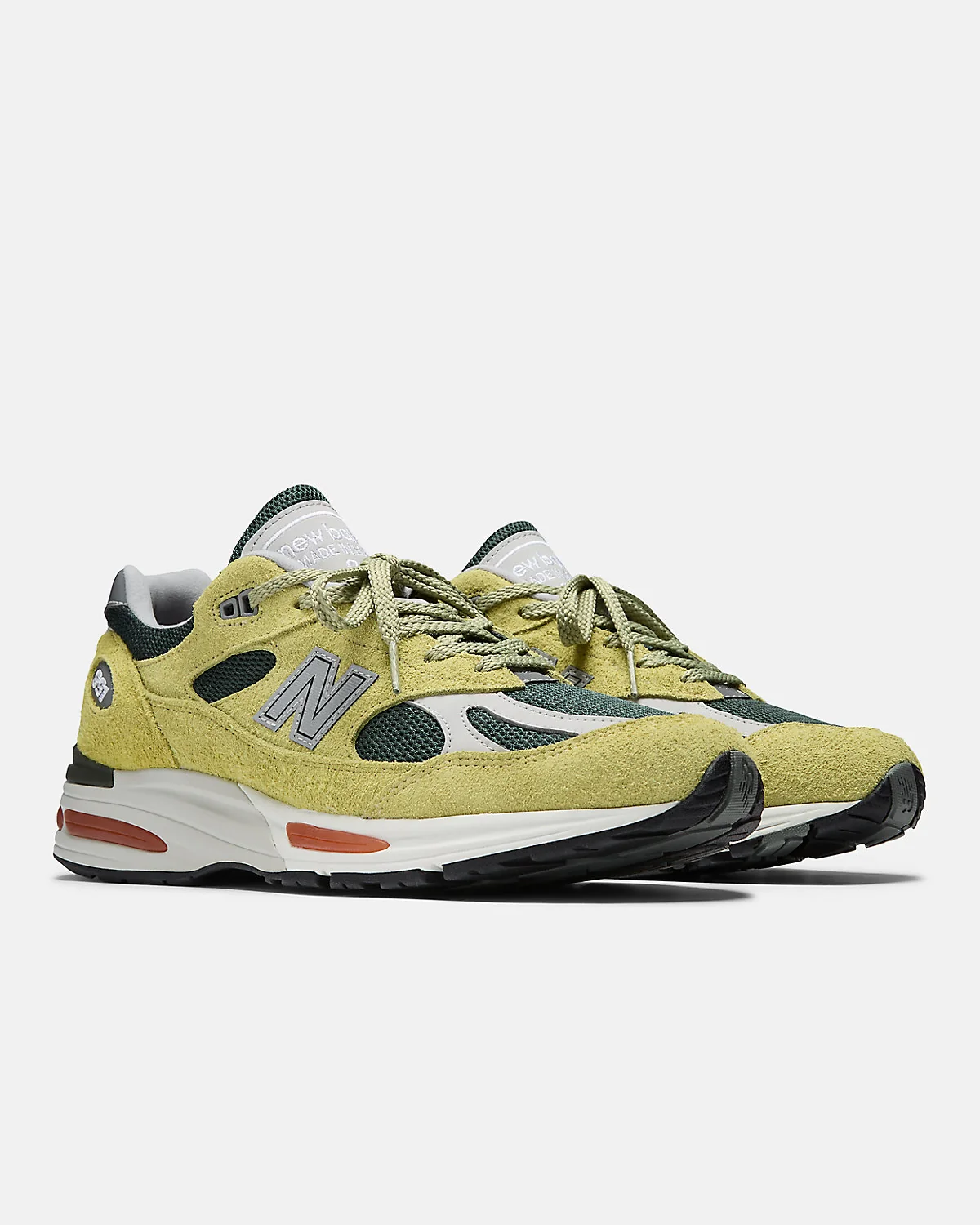 Бежево-зелёные кроссовки New Balance 991v2 с трекинг-зелёными панелями, разносторонний вид.
