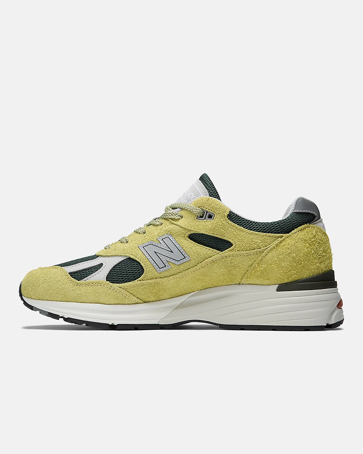 Боковой профиль бежево-зелёных кроссовок New Balance 991v2 с трёхслойной подошвой.