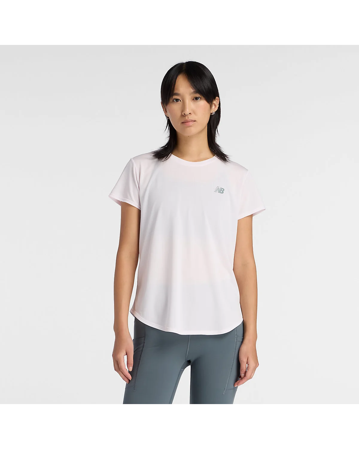 Светло-розовая футболка New Balance с круглым вырезом и вышивкой логотипа на модели.