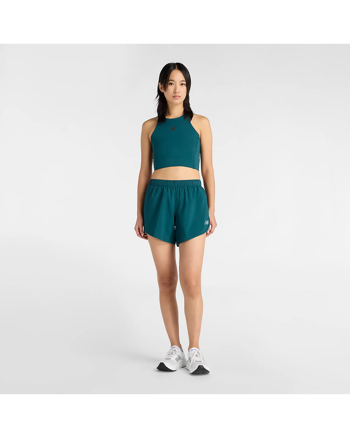 Зелёные шорты New Balance на модели в профиль, вид сбоку.