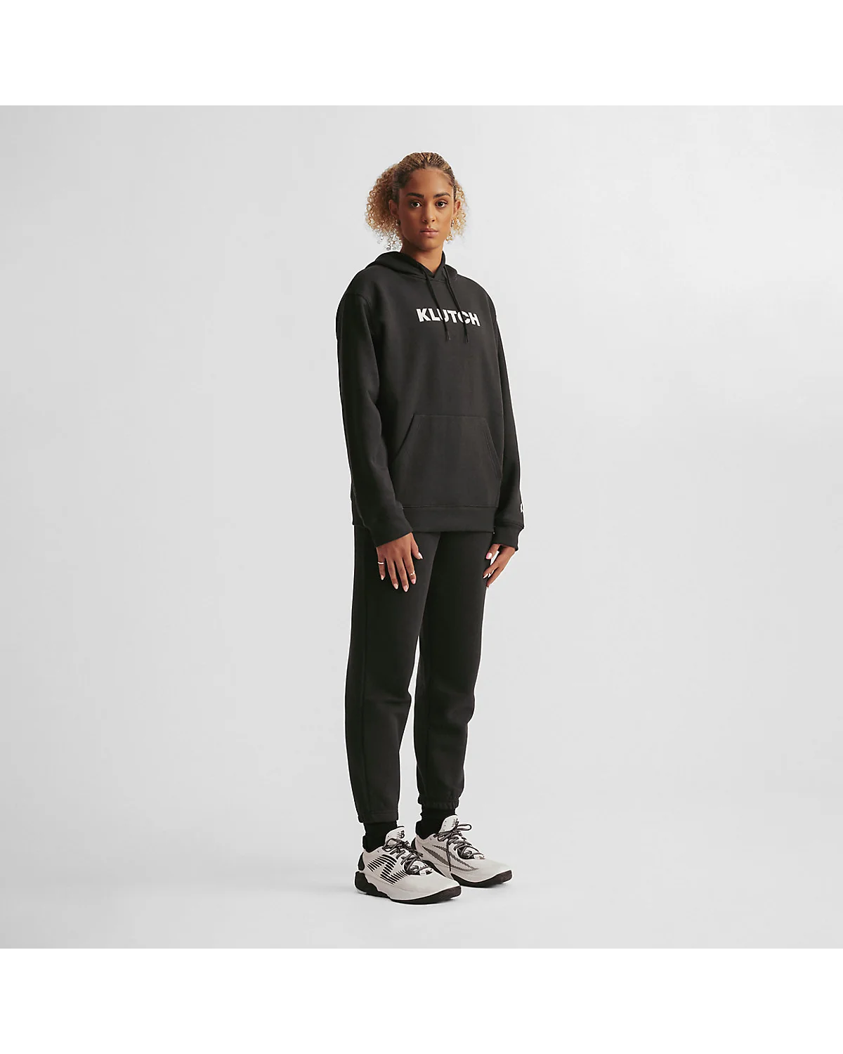 Чёрное флисовое худи New Balance на модели, полный рост, вид сбоку.