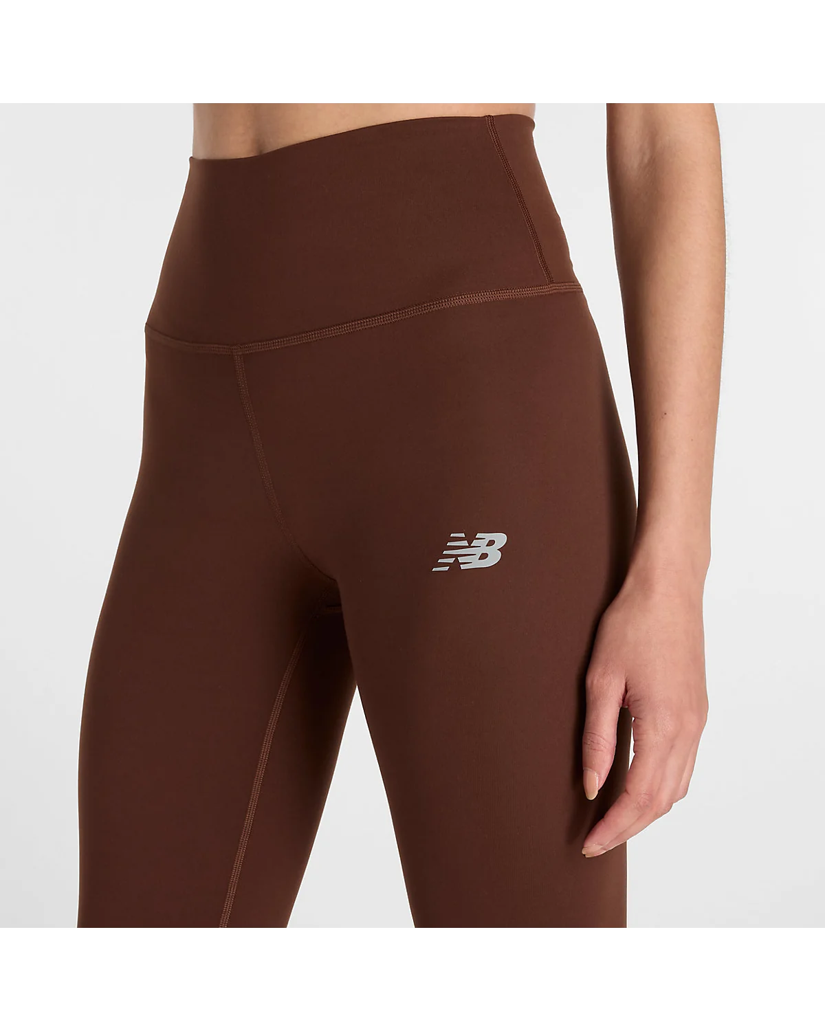 Деталь высокого пояса тёмно-коричневых леггинсов New Balance, крупный план.