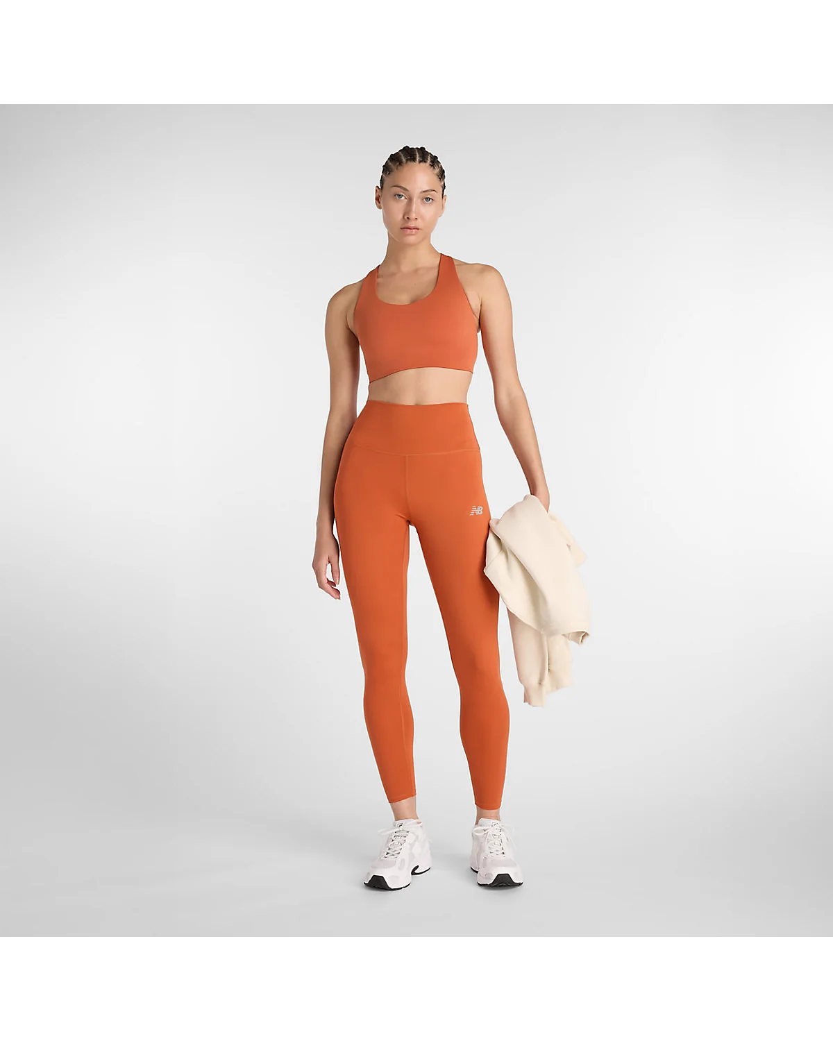 Модель в леггинсах New Balance цвета корицы и топе, полный вид.