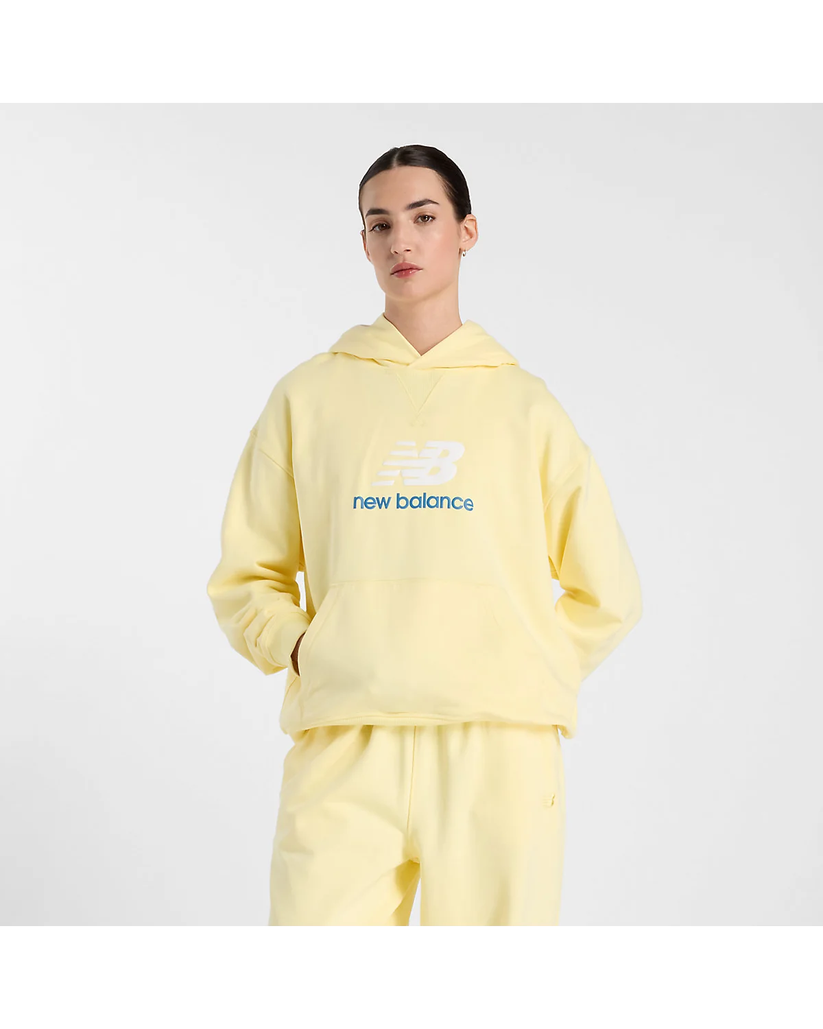 Жёлтая толстовка New Balance Athletics с логотипом на груди, вид спереди.