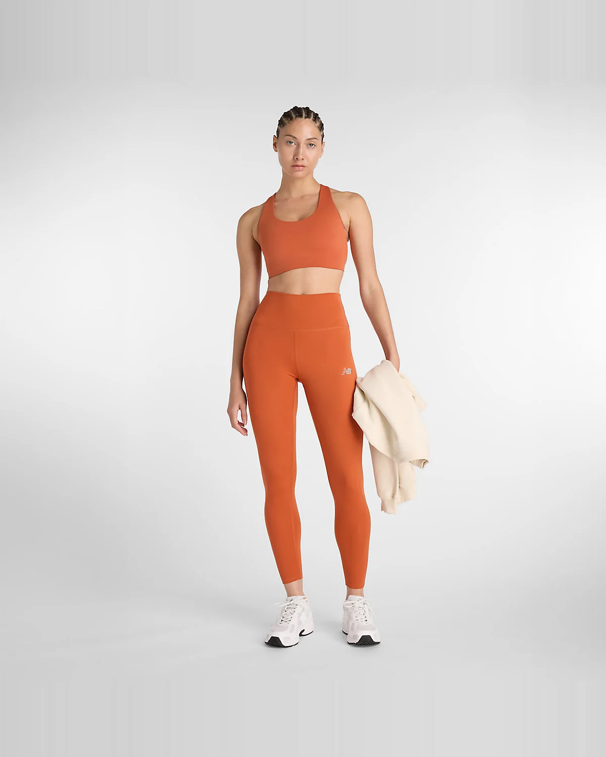 Модель в леггинсах New Balance цвета корицы и топе, полный вид.
