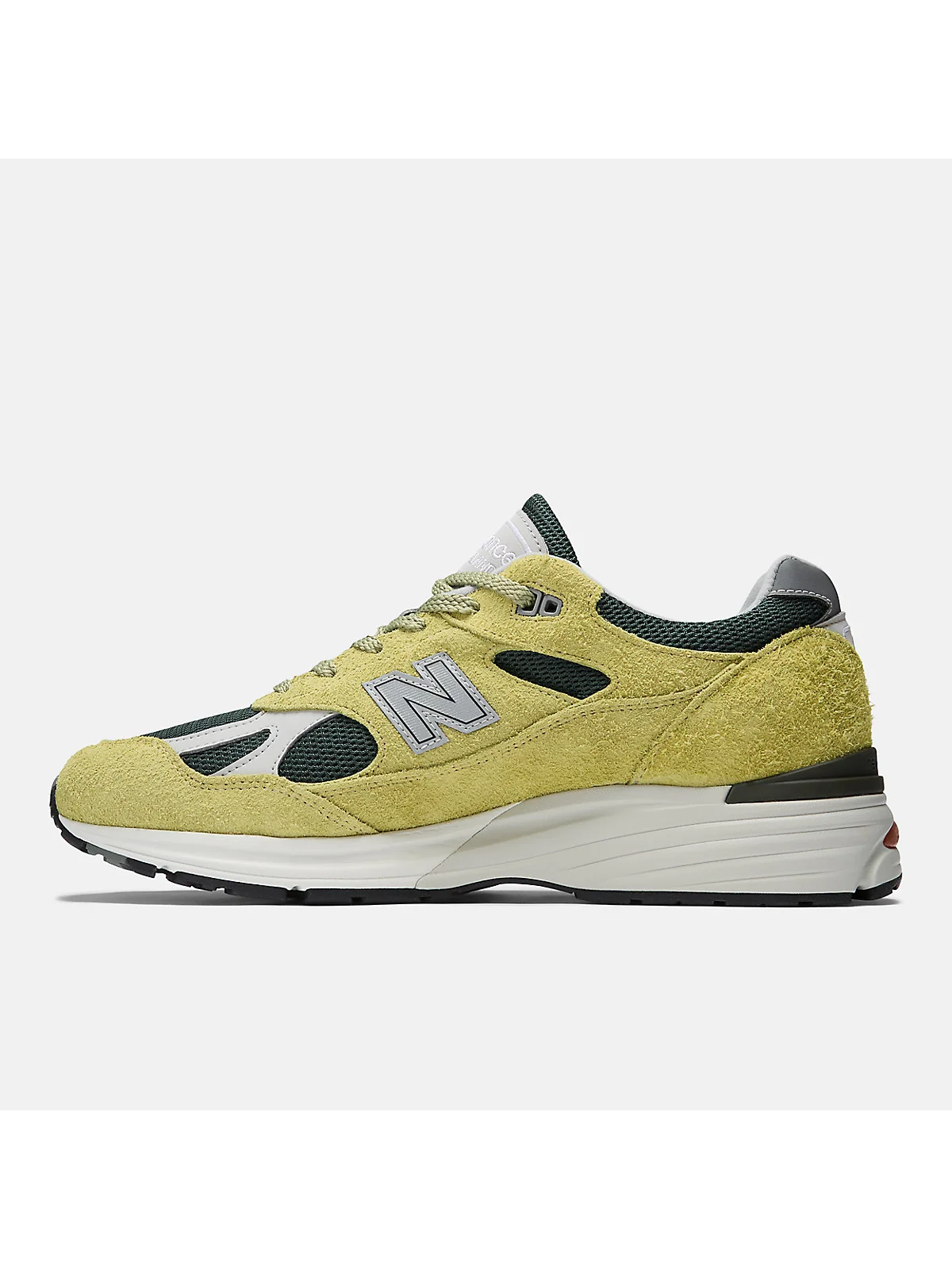 Боковой профиль бежево-зелёных кроссовок New Balance 991v2 с трёхслойной подошвой.