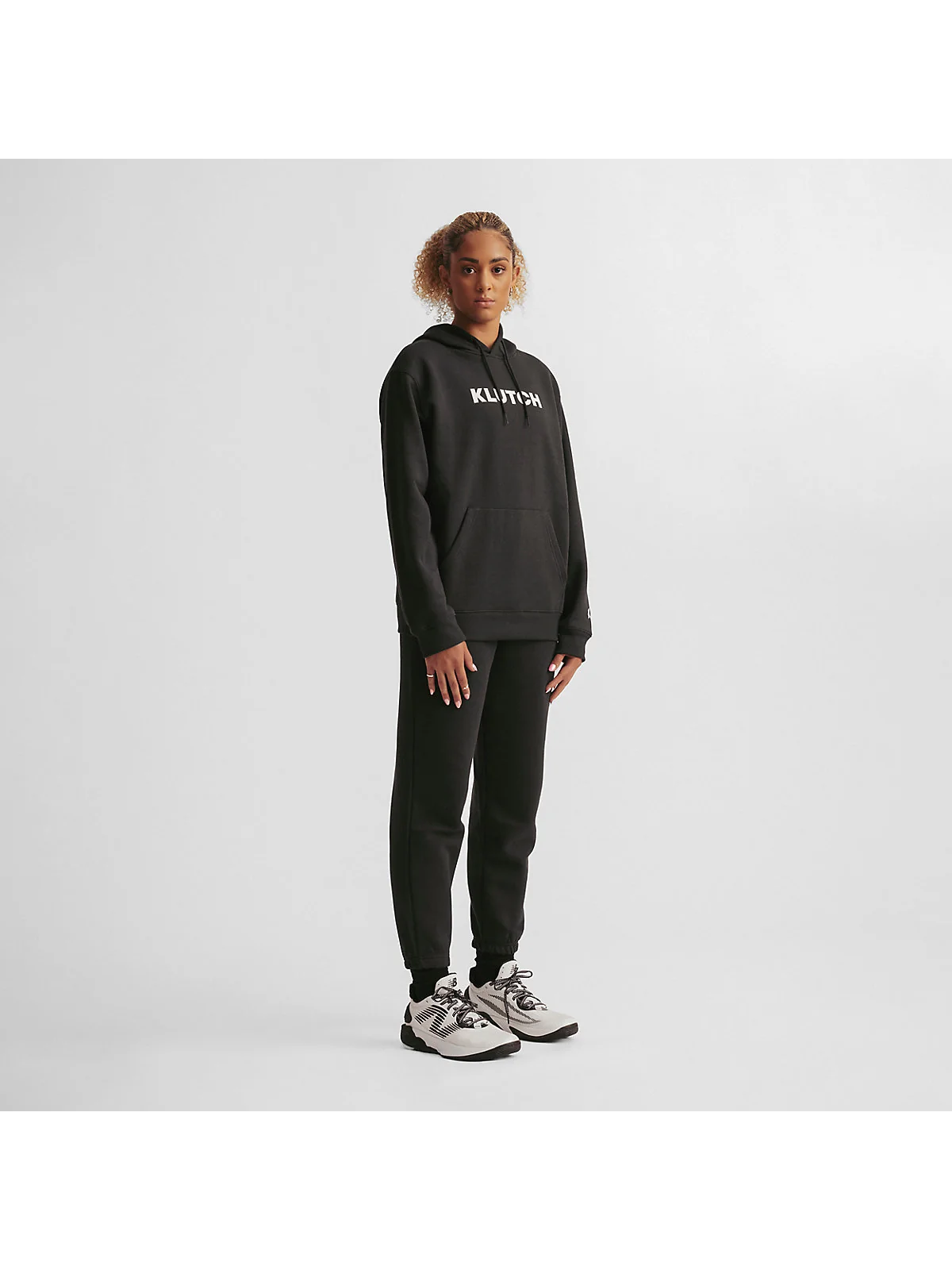 Чёрное флисовое худи New Balance на модели, полный рост, вид сбоку.