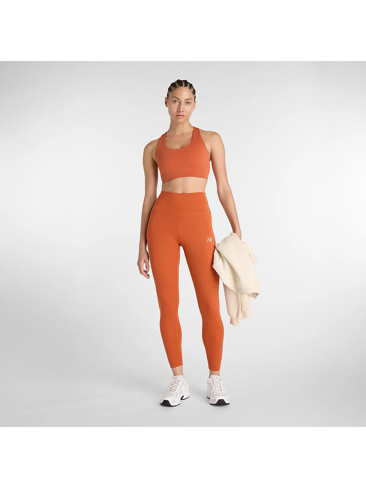 Модель в леггинсах New Balance цвета корицы и топе, полный вид.
