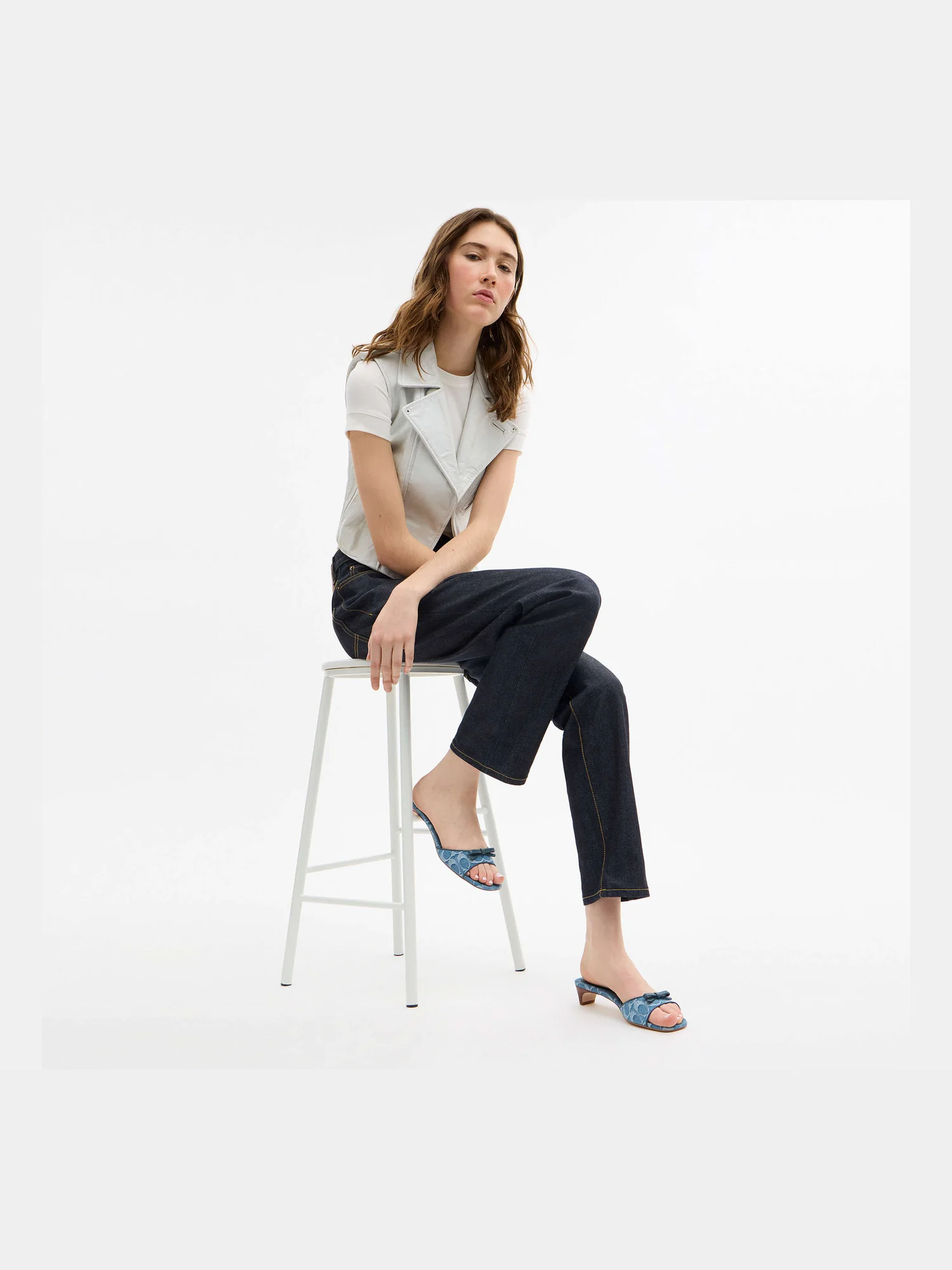 Сандалии Coach Bow Kitten Heel на моделе, вид сидя.